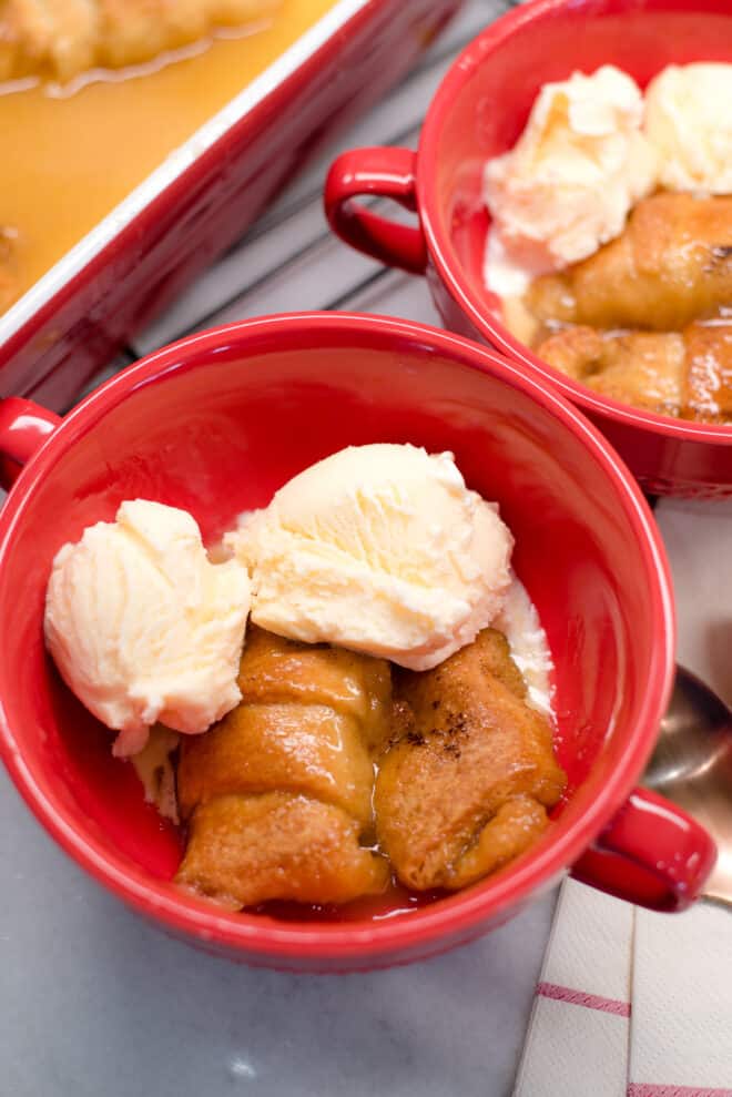Spiced Rum Peach Dumplings in red bowls with scoops of vanilla ice cream on top