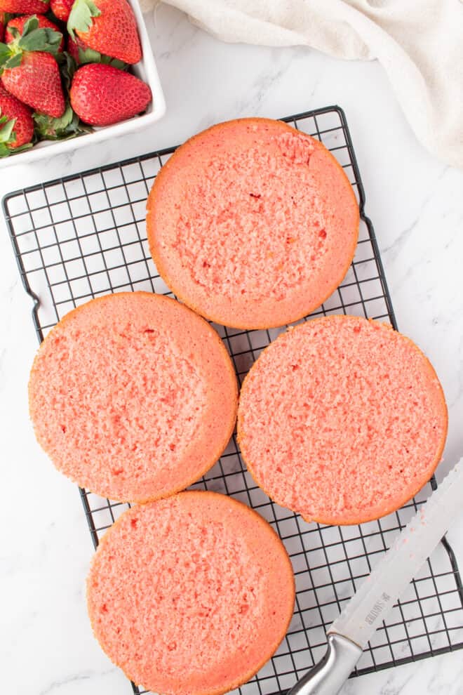 four strawberry layers cooling on a wire rack