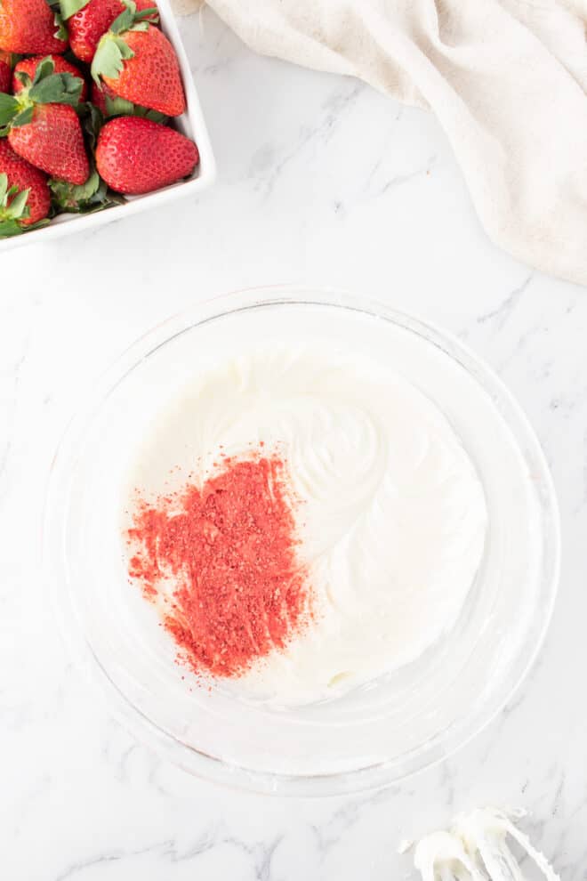 freeze dried strawberry powder being added to cream cheese frosting