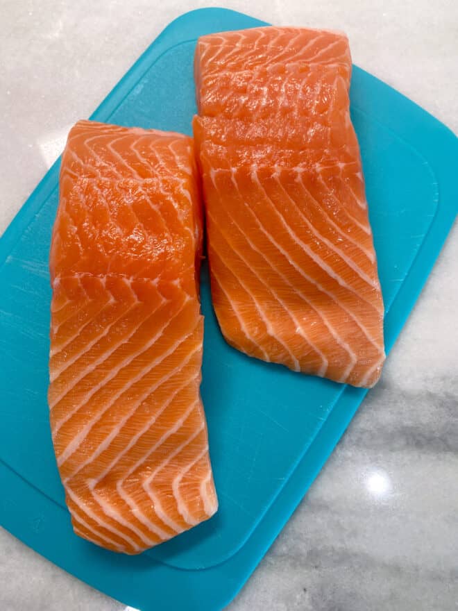 fresh salmon filets on a blue cutting board