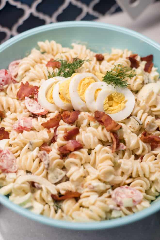 Dill Pickle Pasta Salad in blue bowl garnished with sliced hardboiled eggs