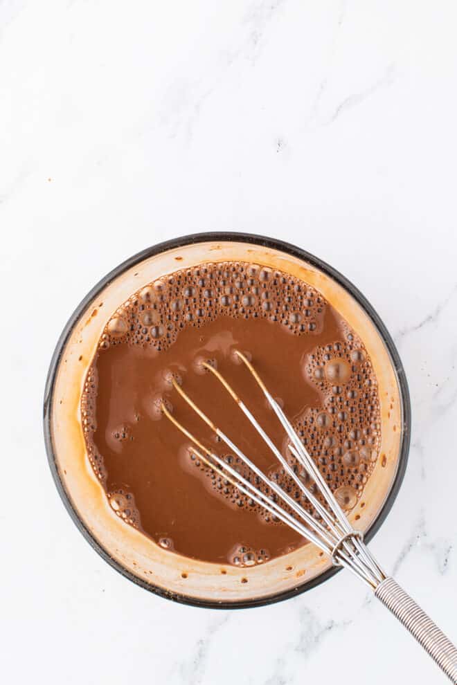 chocolate and hot water mixed together in a glass bowl. 