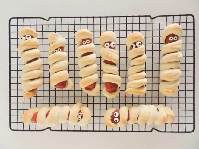 Mummy Dogs cooling on a rack after edible googly eyes have been placed on the mummy dogs