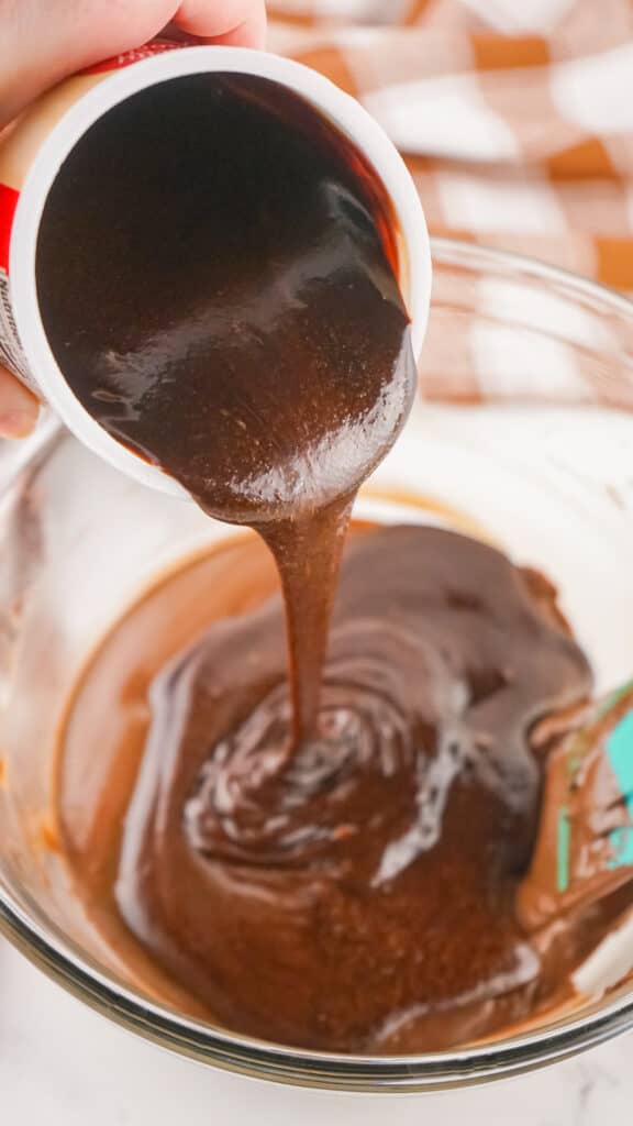 melted chocolate frosting pouring into bowl of melted chocolate chips