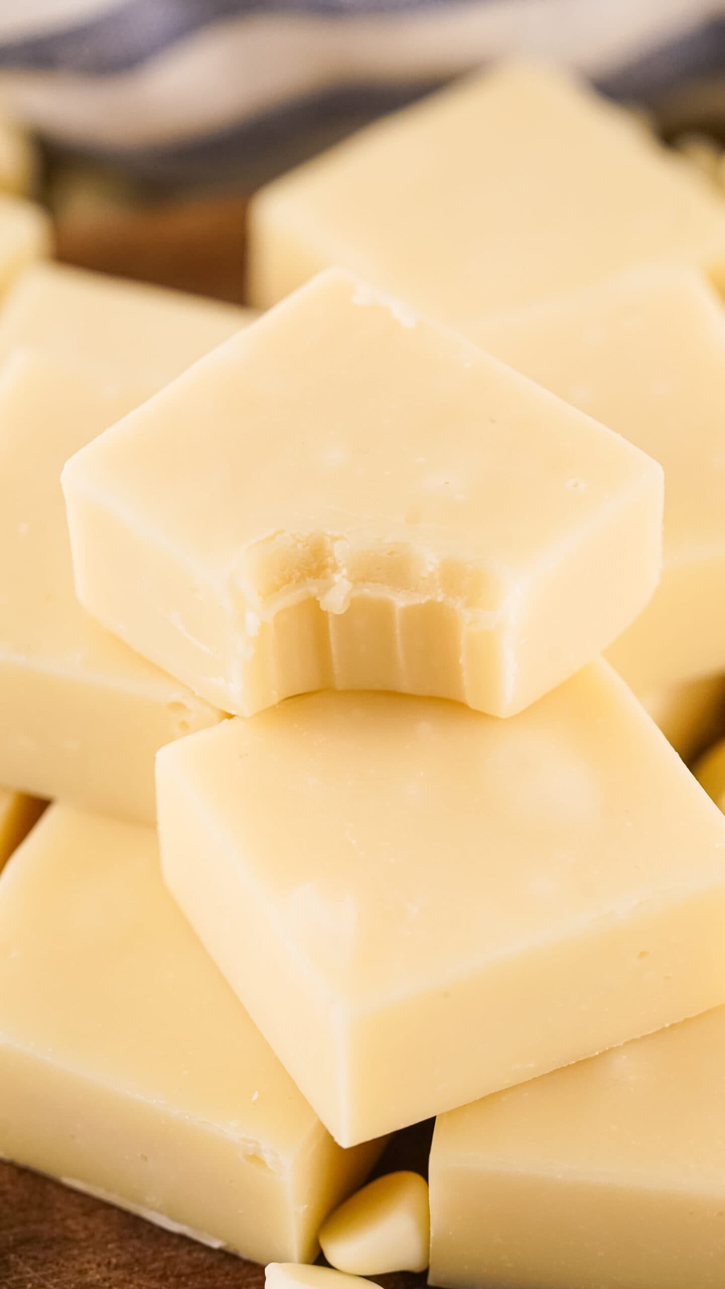 close up photo of vanilla fudge squares with a bite taken out of the top square