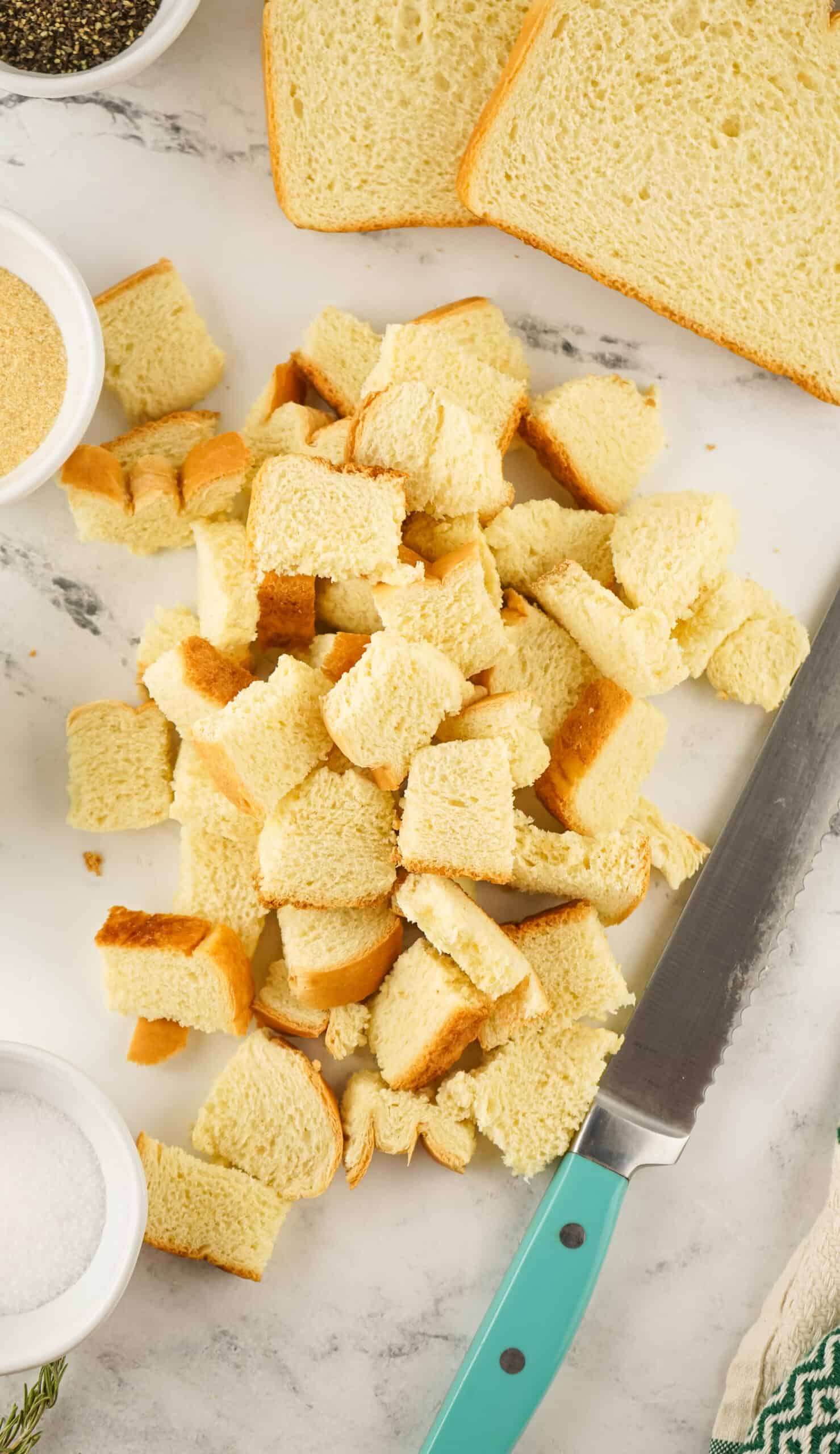 bread being cut into one inch cubes to make croutons