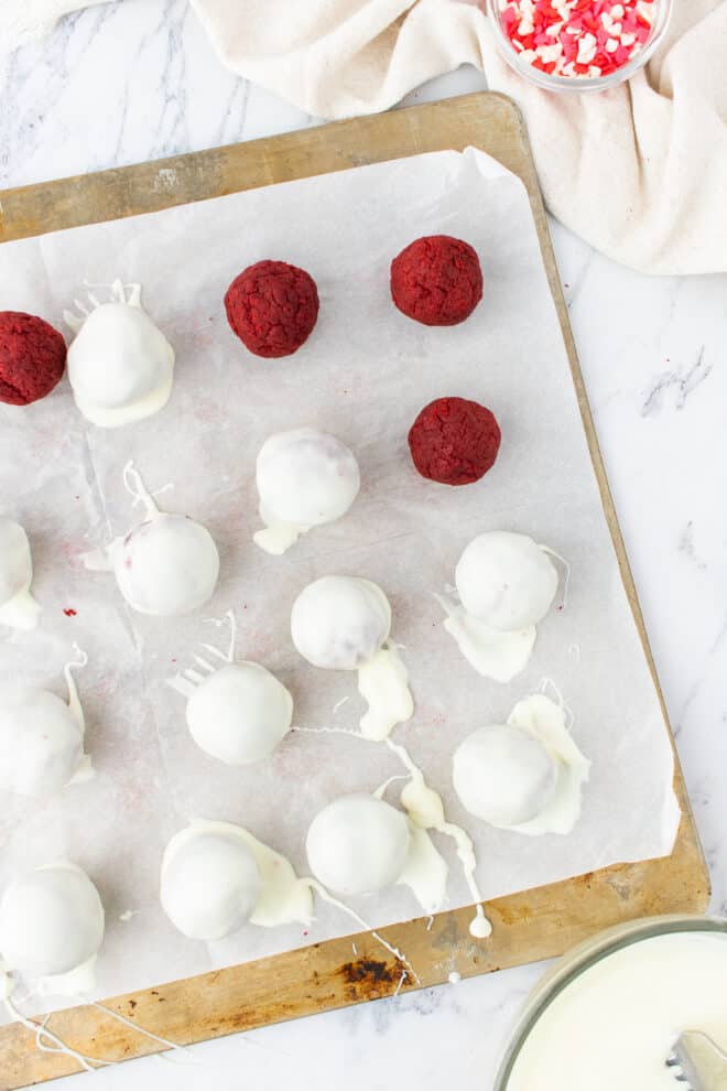 red velvet cake balls dipped in white chocolate on parchment paper