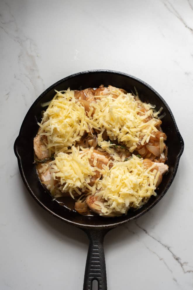 french onion chicken bake covered in grated cheese before baking for 10 minutes