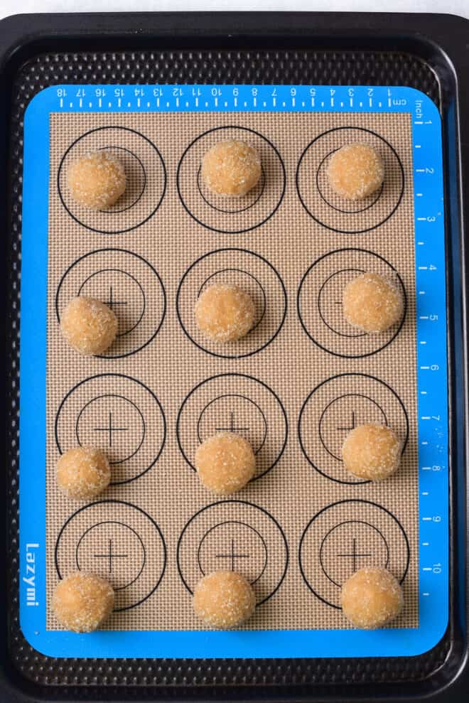 peanut butter cookie balls on baking sheet lined with a silicone pad