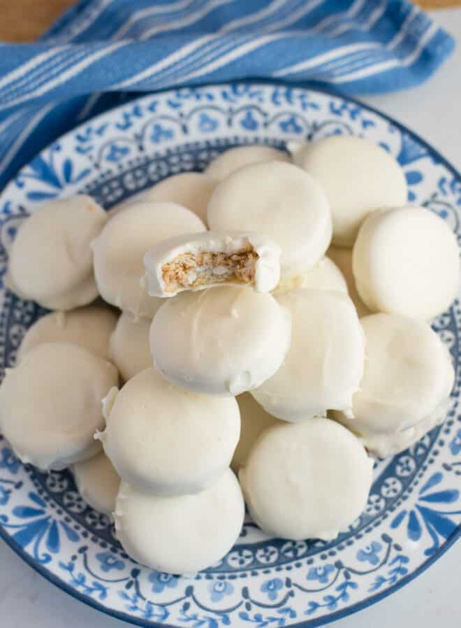 White chocolate-covered peanut butter Ritz crackers stacked on a blue and white serving platter