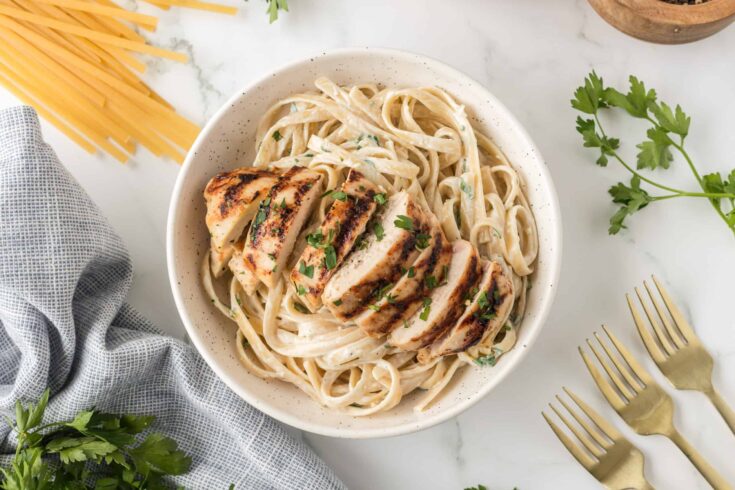 Close Up photo of creamy fettuccini with a grilled sliced chicken breast on top