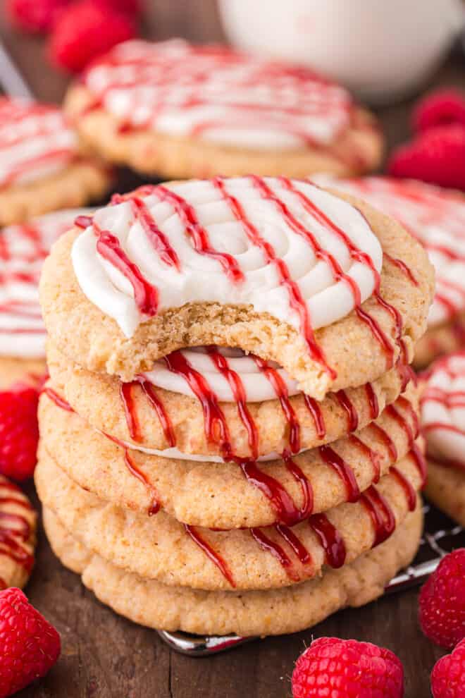 Sugar Cookies Topped With A Cream cheese frosting and Raspberry drizzle stacked on top of each other