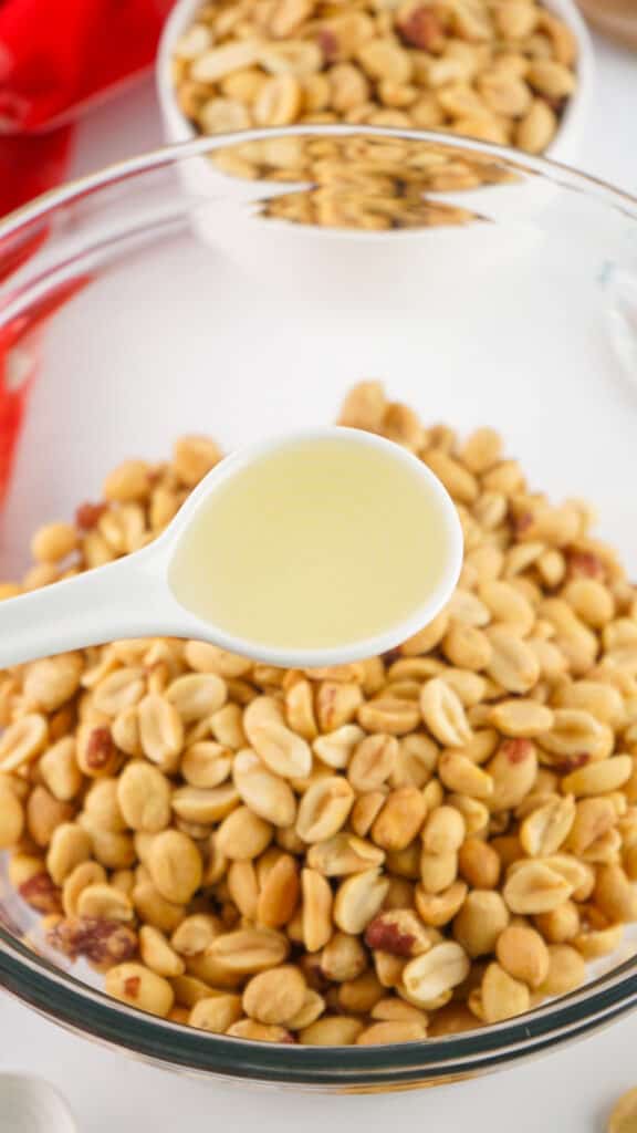 a tablespoon of oil added to peanuts in a bowl