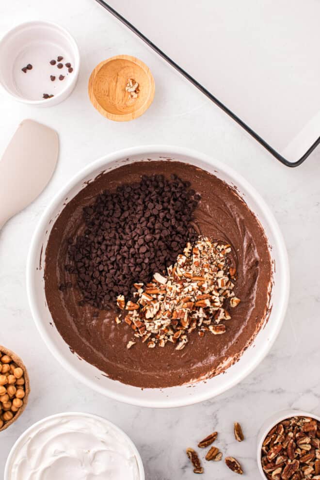 chocolate chips and pecans added to chocolate cake batter in mixing bowl