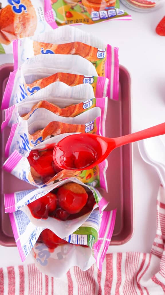 adding strawberry pie filling to each bag of mini muffins