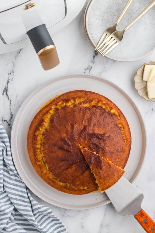 Air Fryer Cornbread on a white serving dish with one slice being lifted up