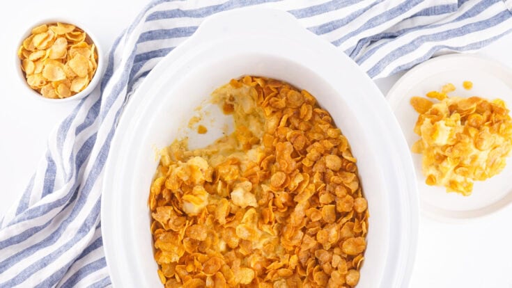 Crockpot Funeral Potatoes - Cheesy Potato Casserole topped with crispy cornflakes in a white slow cooker
