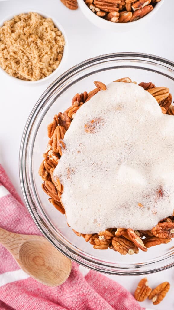 egg whites on top of pecans in a clear bowl