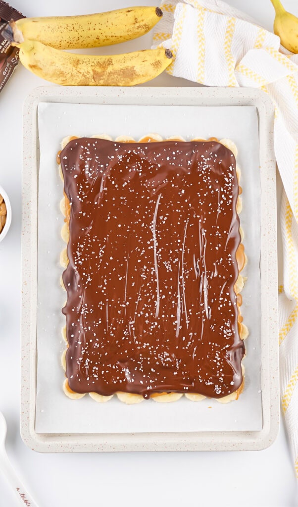 sea salt sprinkled over the top of dark chocolate in a sheet pan