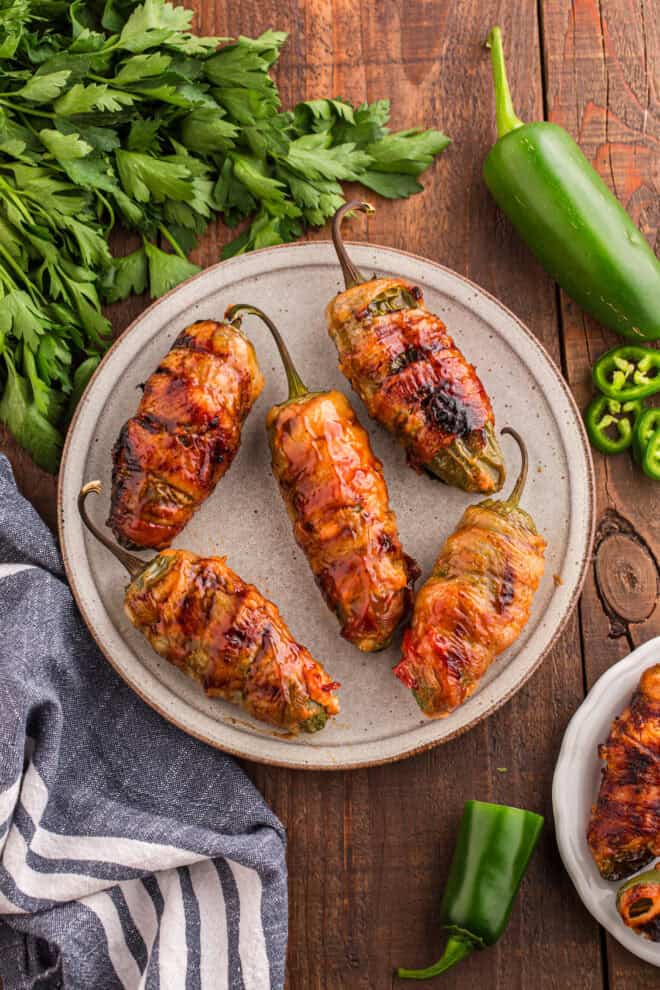Jalapeno Poppers filled with cream cheese, brisket and wrapped in bacon on a white serving plate