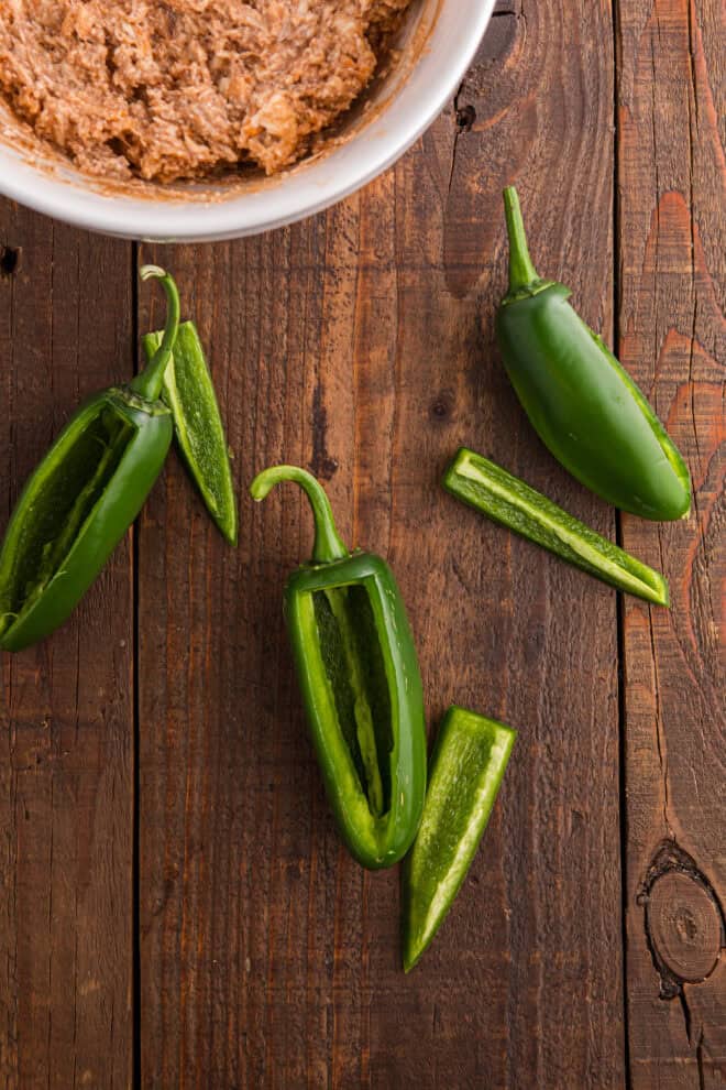 Sliced Jalapeno peppers on a dark brown wood table