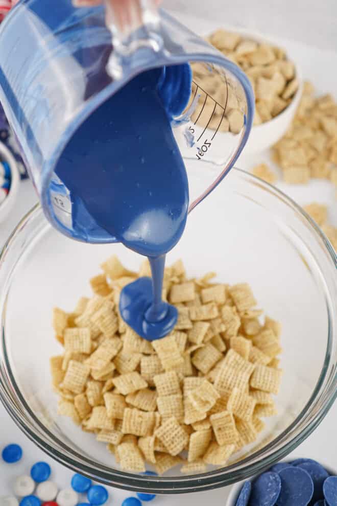 Blue melted candy melts being poured over Chex cereal