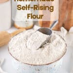 Homemade Self-Rising Flour in a bowl with a scoop on top with a text overlay for Pinterest
