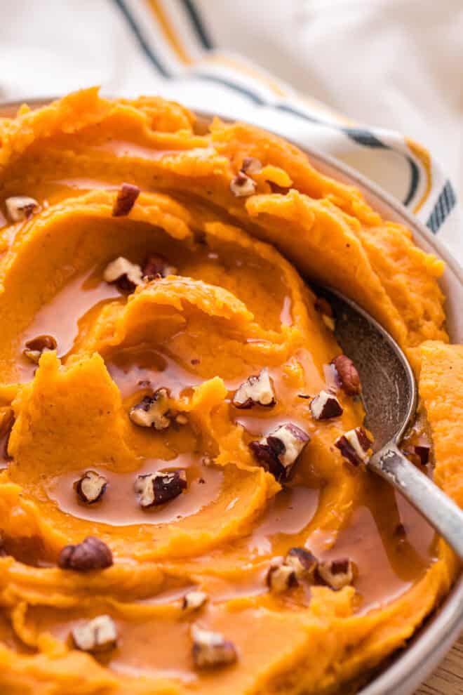sweet potatoes whipped and ready to serve sprinkled with pecans and maple syrup on the side