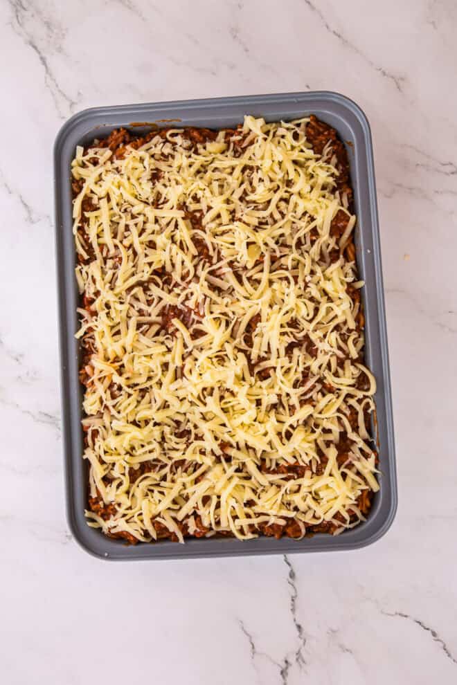 million dollar spaghetti casserole topped with cheese before baking