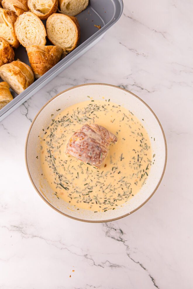 croissants cut into 4ths and being dipped into egg custard